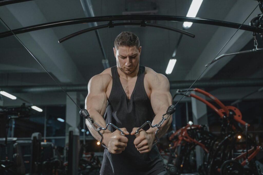 A strong man exercising on a cable crossover machine in a gym setting.